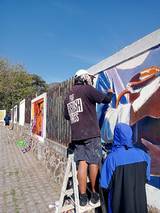 Artistas trabajan en la elaboración de un mural en calles de Tlayacapan. / Cortesía | Norberto Tozcano